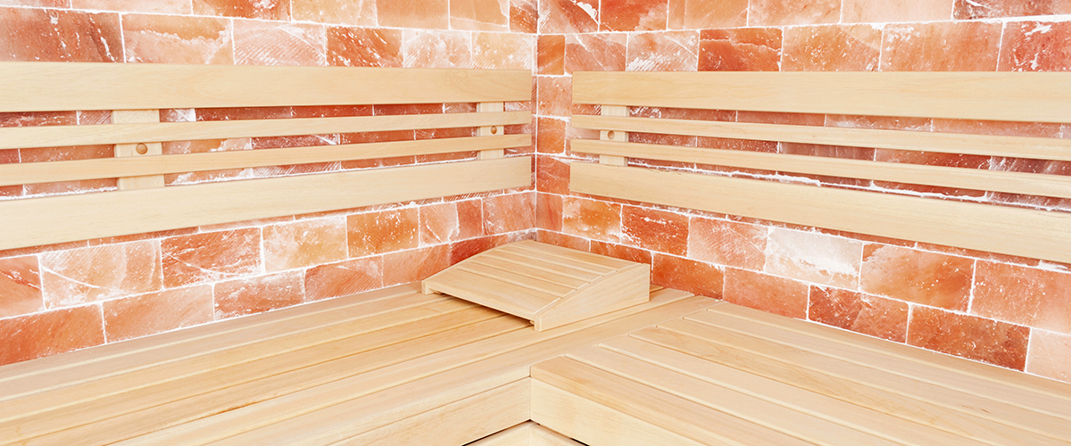 Wooden bench, salt wall and headrest support in sauna room as relaxation concept
