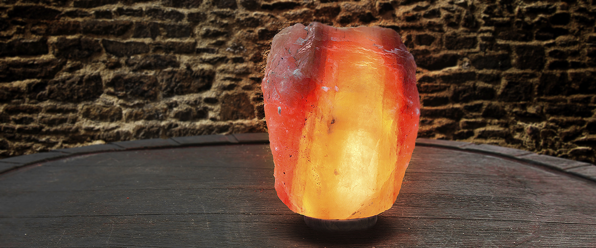 Himalayan salt as a lamp on an old wooden table in front of a stone wall